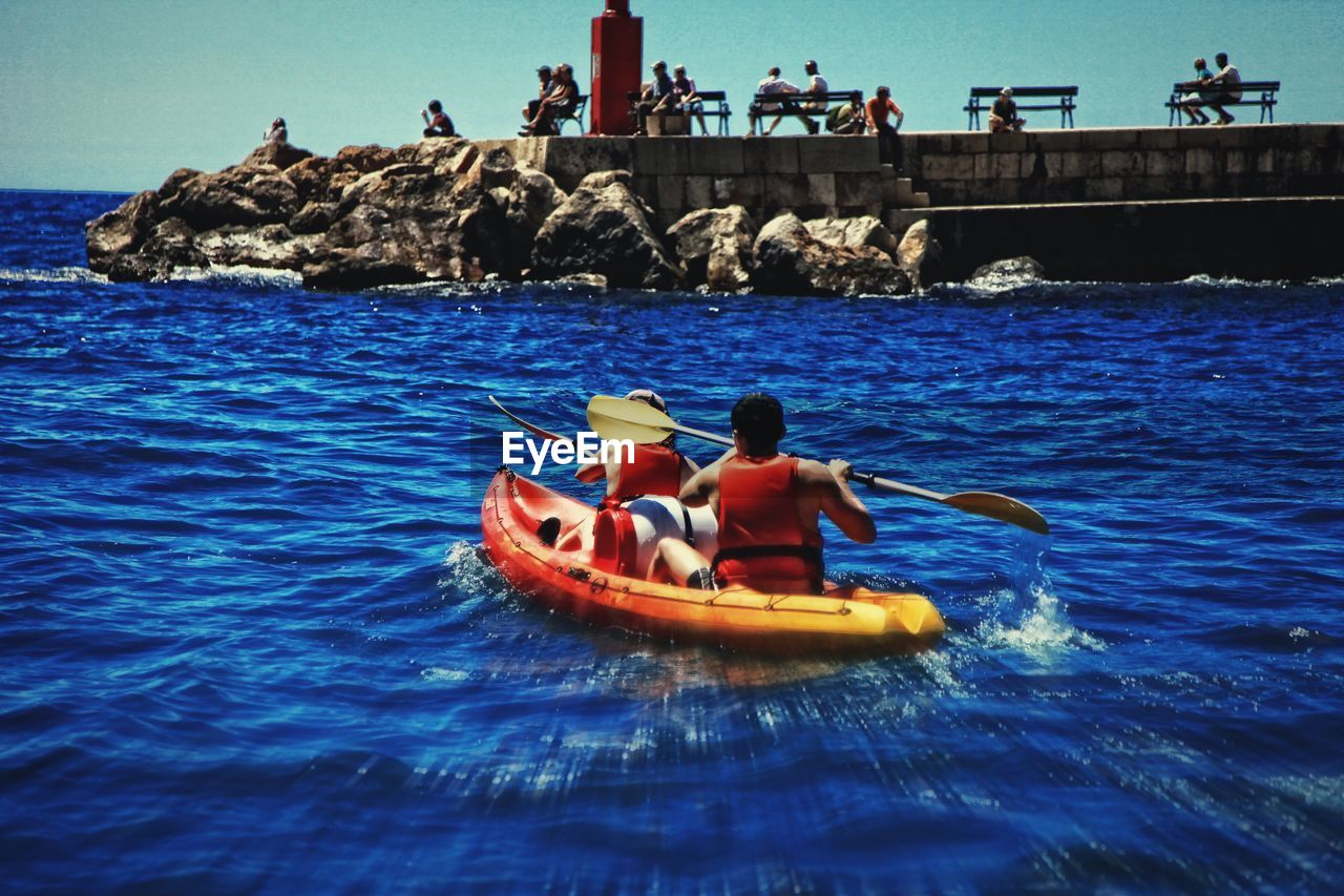 People in boat on sea against sky