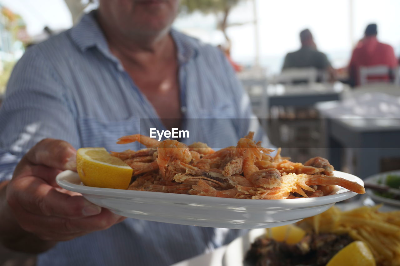 Midsection of man holding seafood in plate