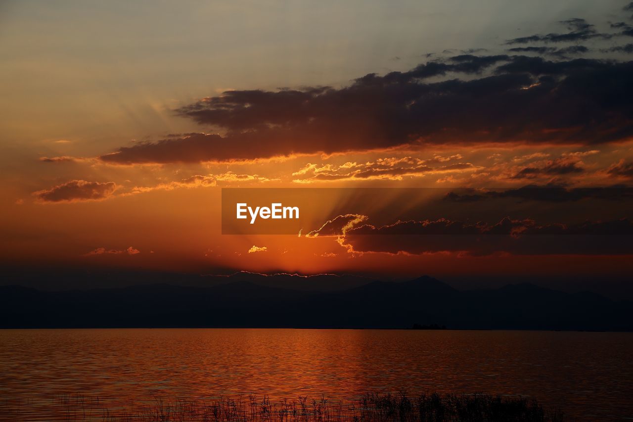 Scenic view of sea against dramatic sky during sunset