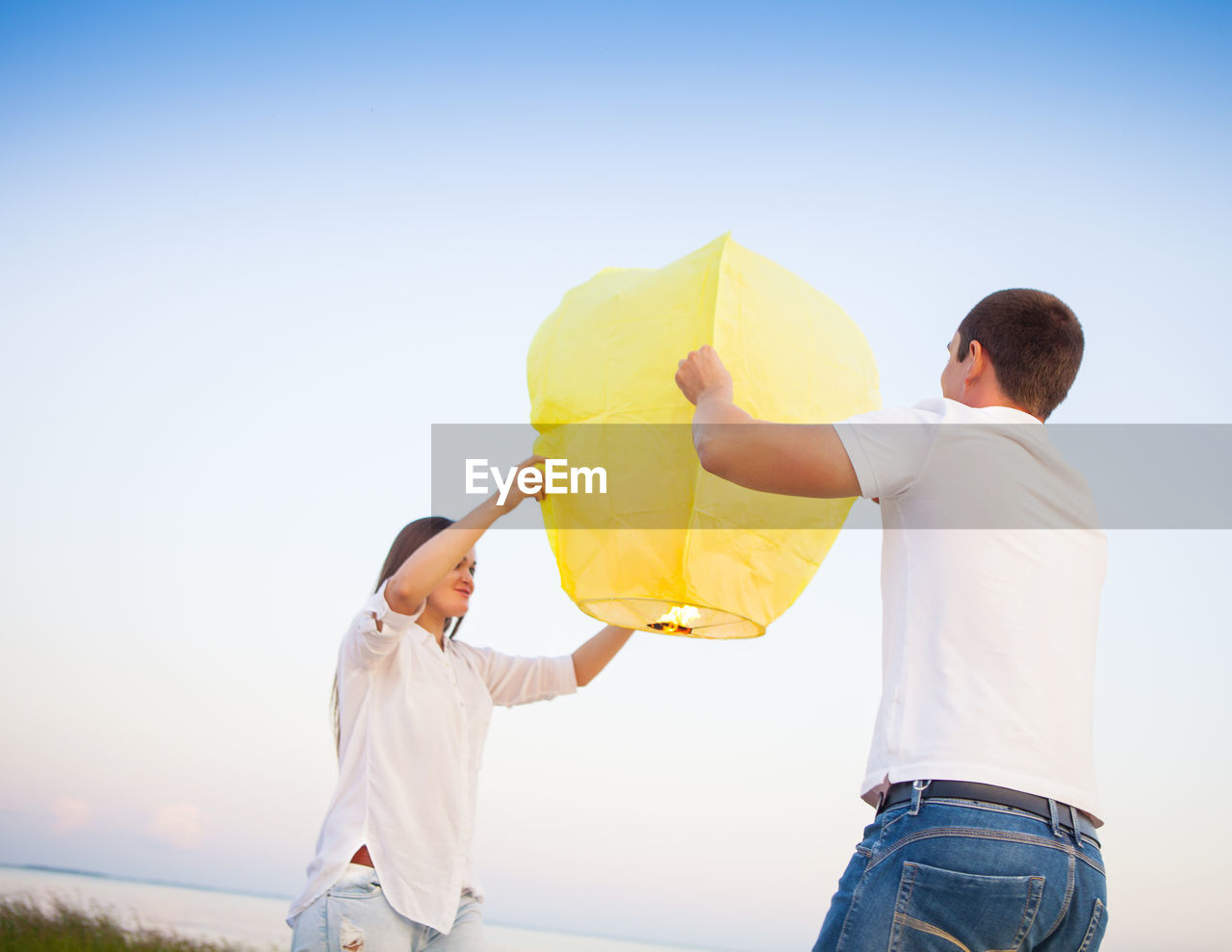 FULL LENGTH OF FATHER HOLDING DAUGHTER AGAINST SKY