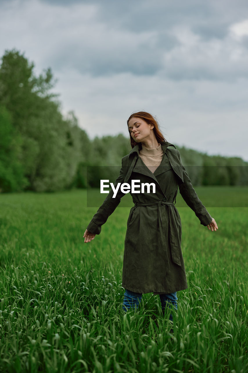 Young woman standing with eyes closed on green grass