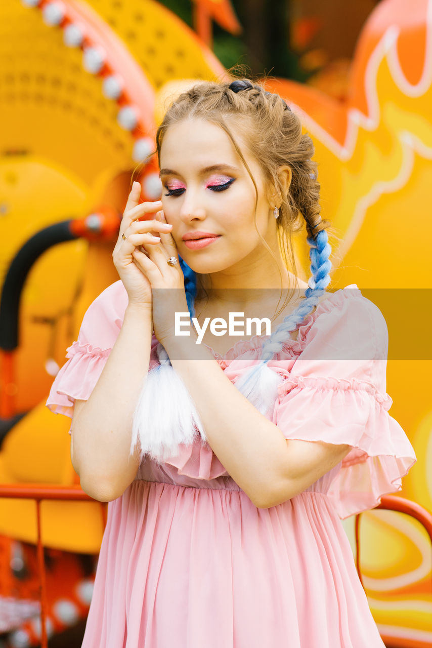Sensual caucasian young woman with blue pigtails with bright makeup in an amusement park