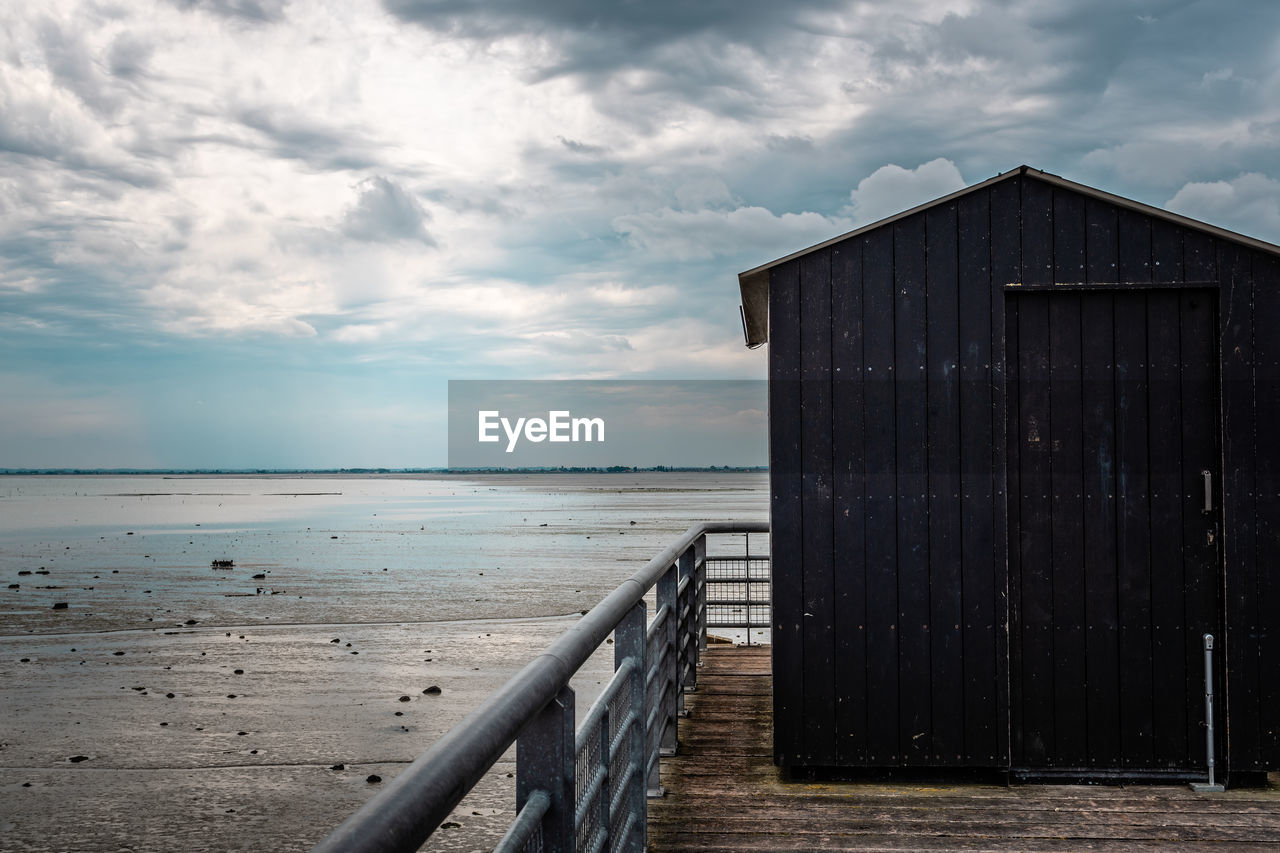 WOODEN STRUCTURE ON SEA SHORE AGAINST SKY