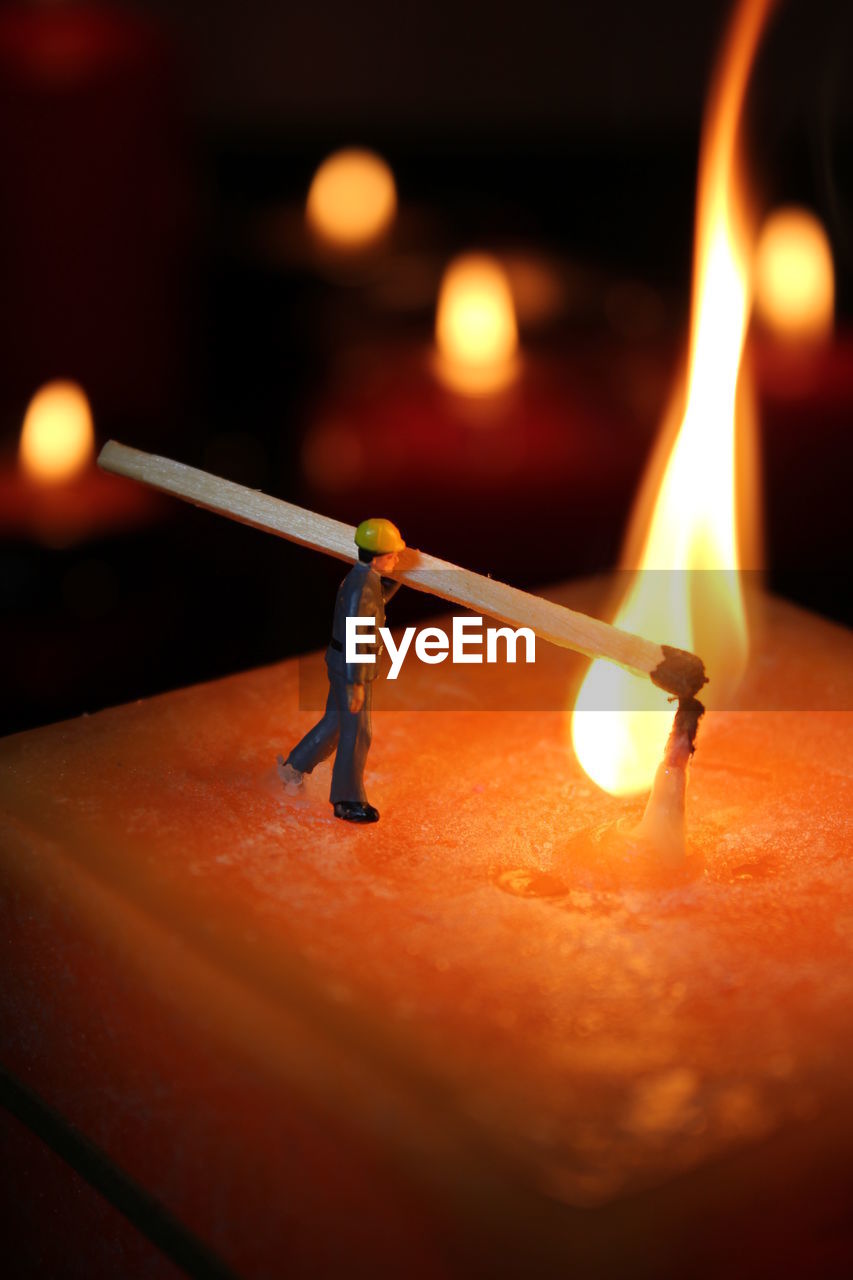 Close-up of figurine lighting candle