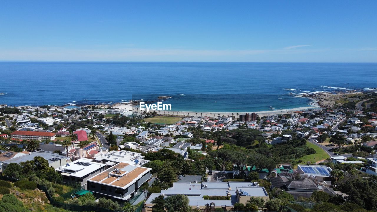 high angle view of townscape by sea against clear blue sky