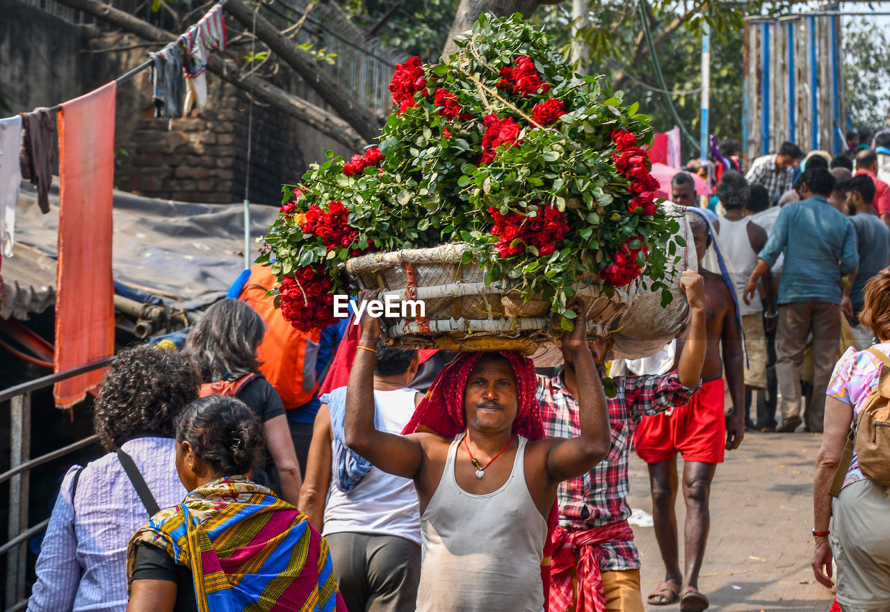 GROUP OF PEOPLE WALKING IN FRONT OF PLANTS