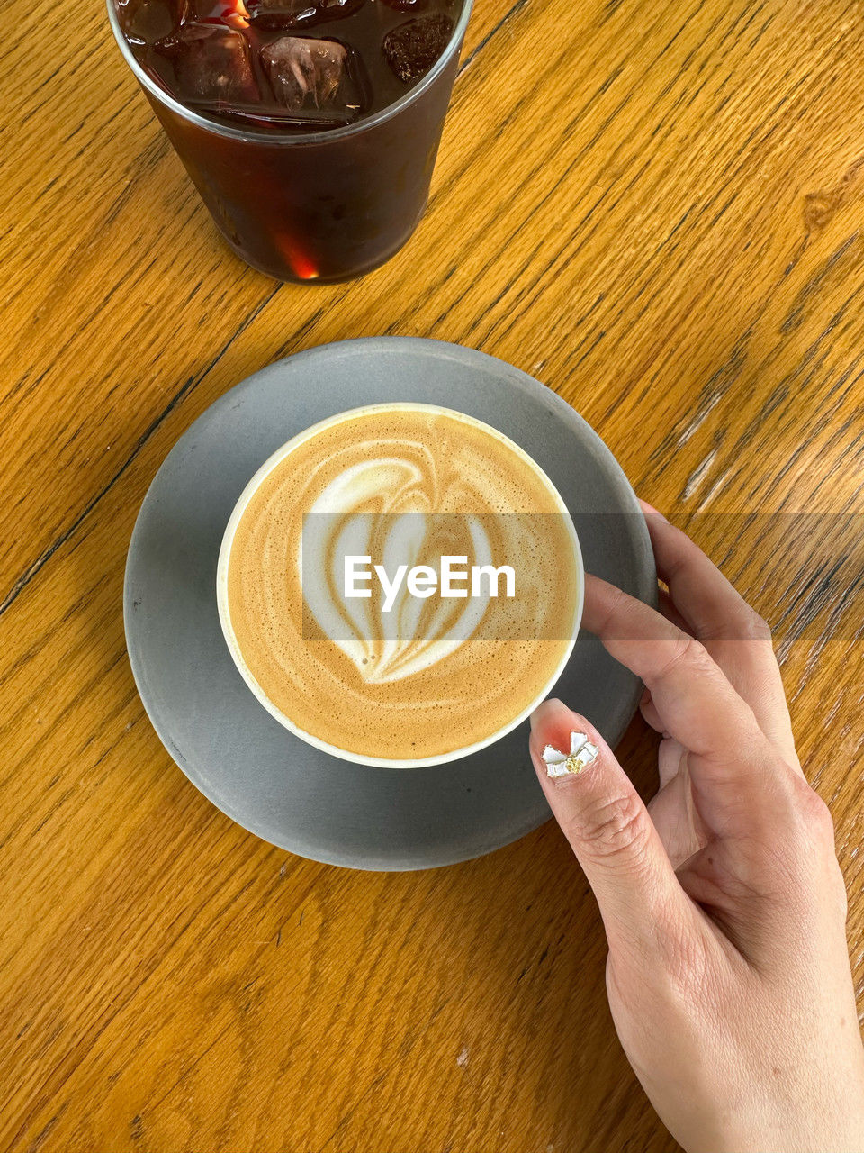 cropped hands of person holding coffee on table