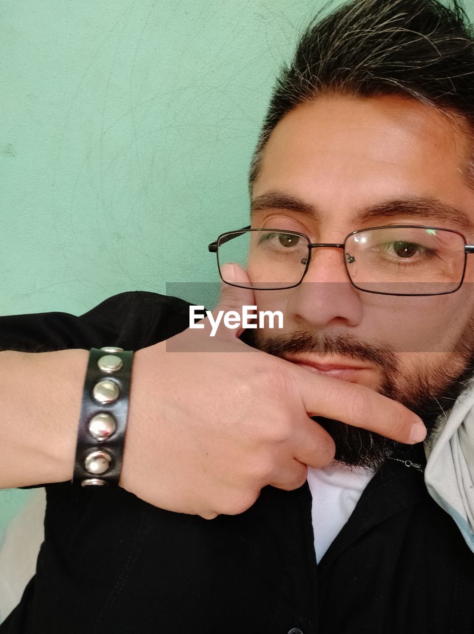Portrait of man wearing eyeglasses against wall