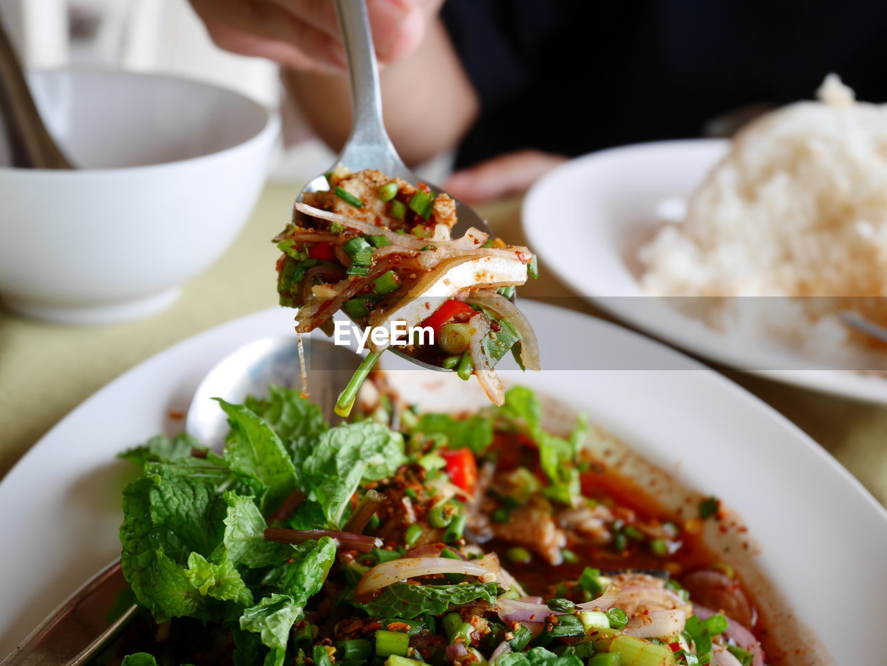 Cropped image of person with food in spoon at table