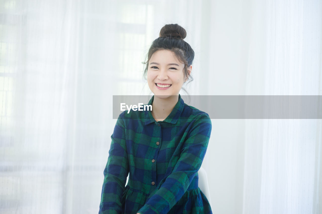 Portrait of smiling young woman sitting at home