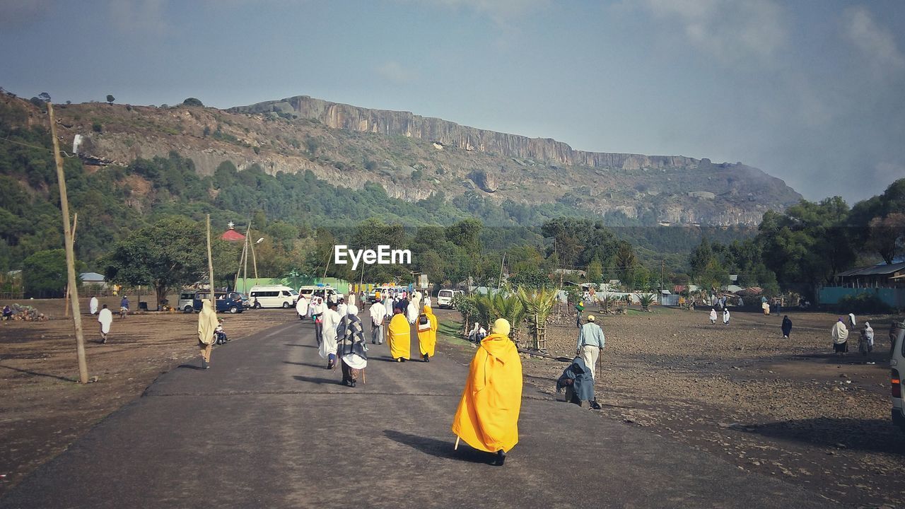 People walking on road against mountains