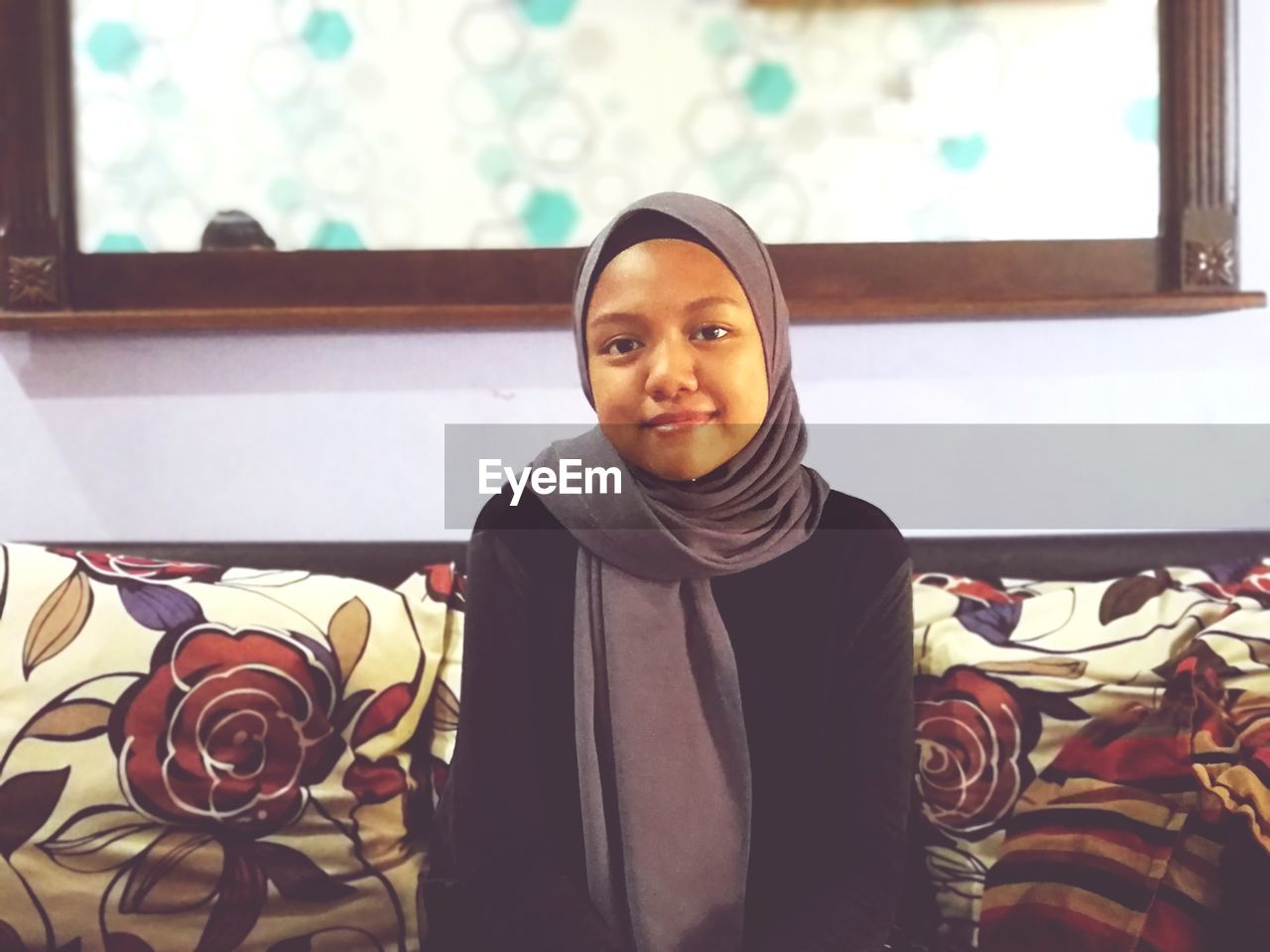 Portrait of smiling girl wearing hijab while sitting at home