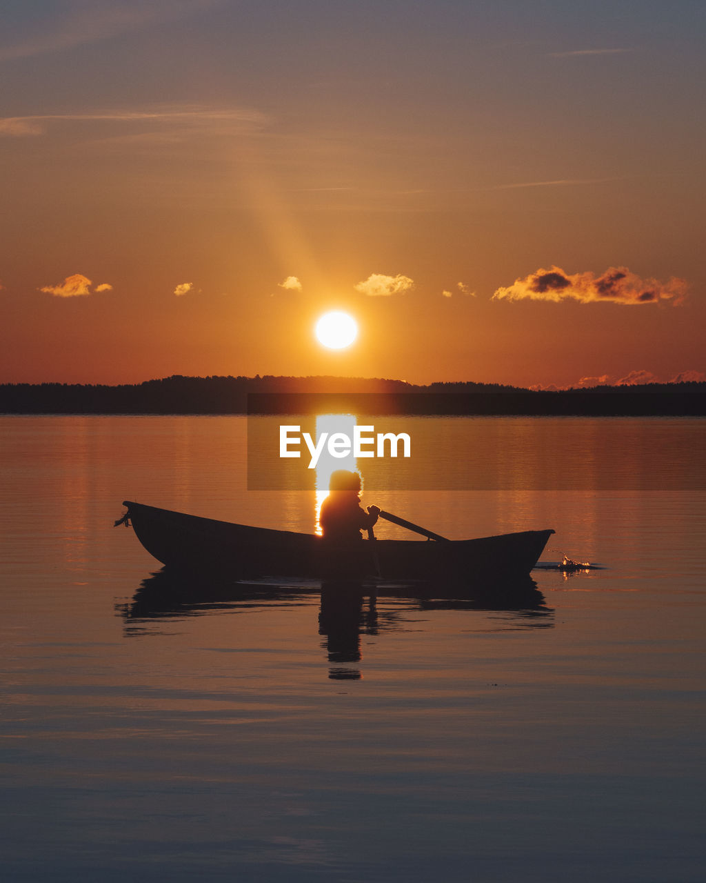 Silhouette boat in lake against sky during sunset