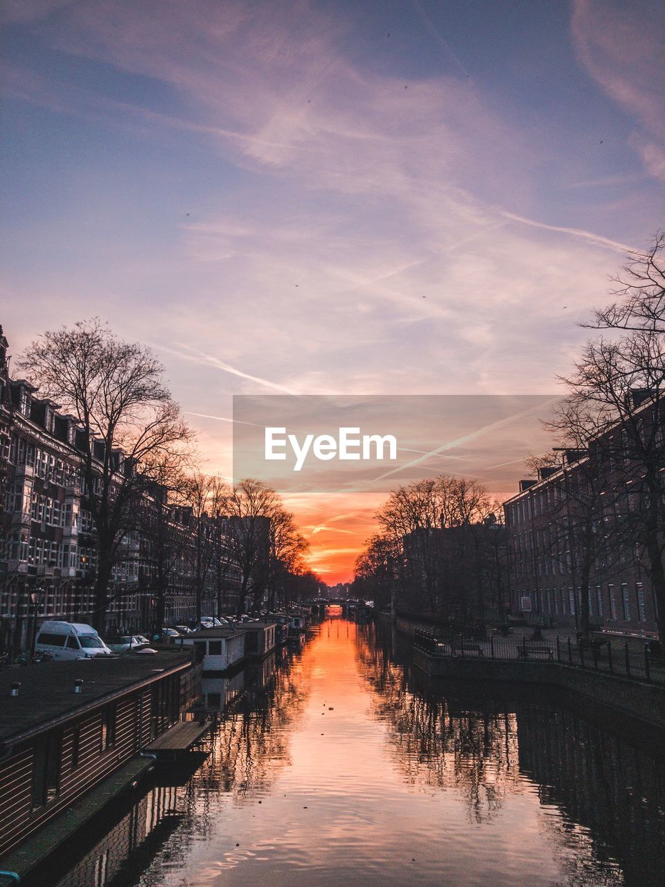 Canal amidst buildings against sky during sunset