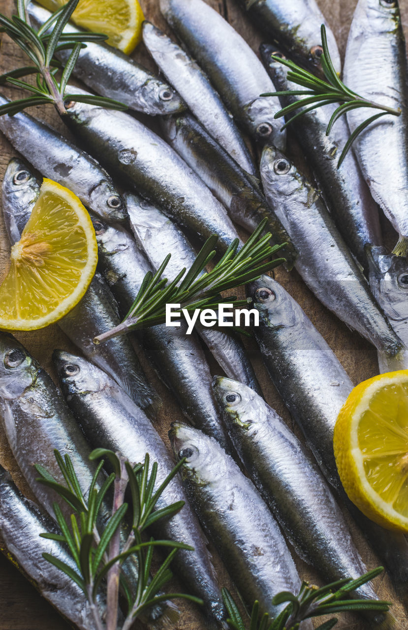 High angle view of fishes and lemon slices with rosemary on table