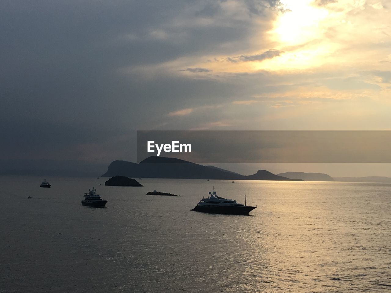 BOAT SAILING IN SEA AGAINST SUNSET SKY