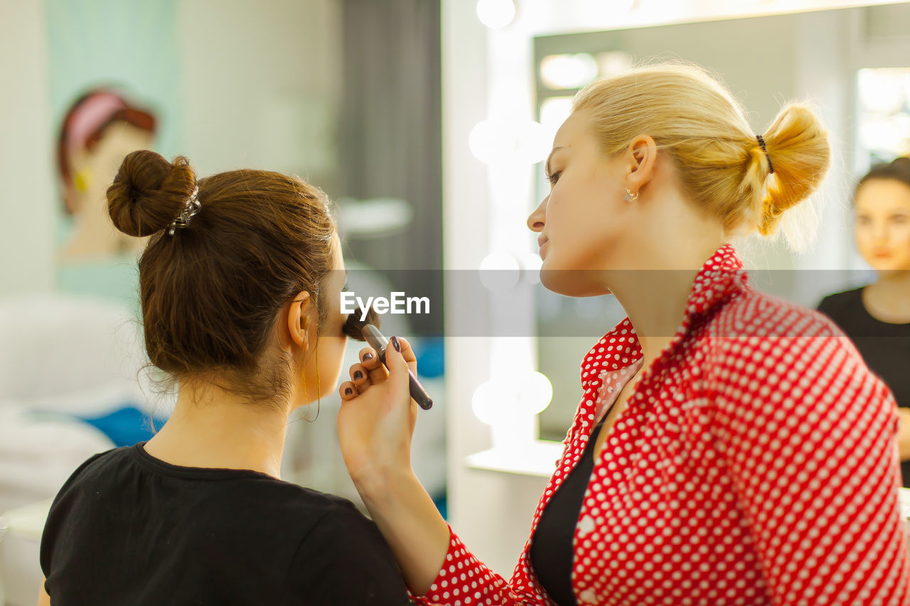 Beautician applying make-up to customer in beauty spa