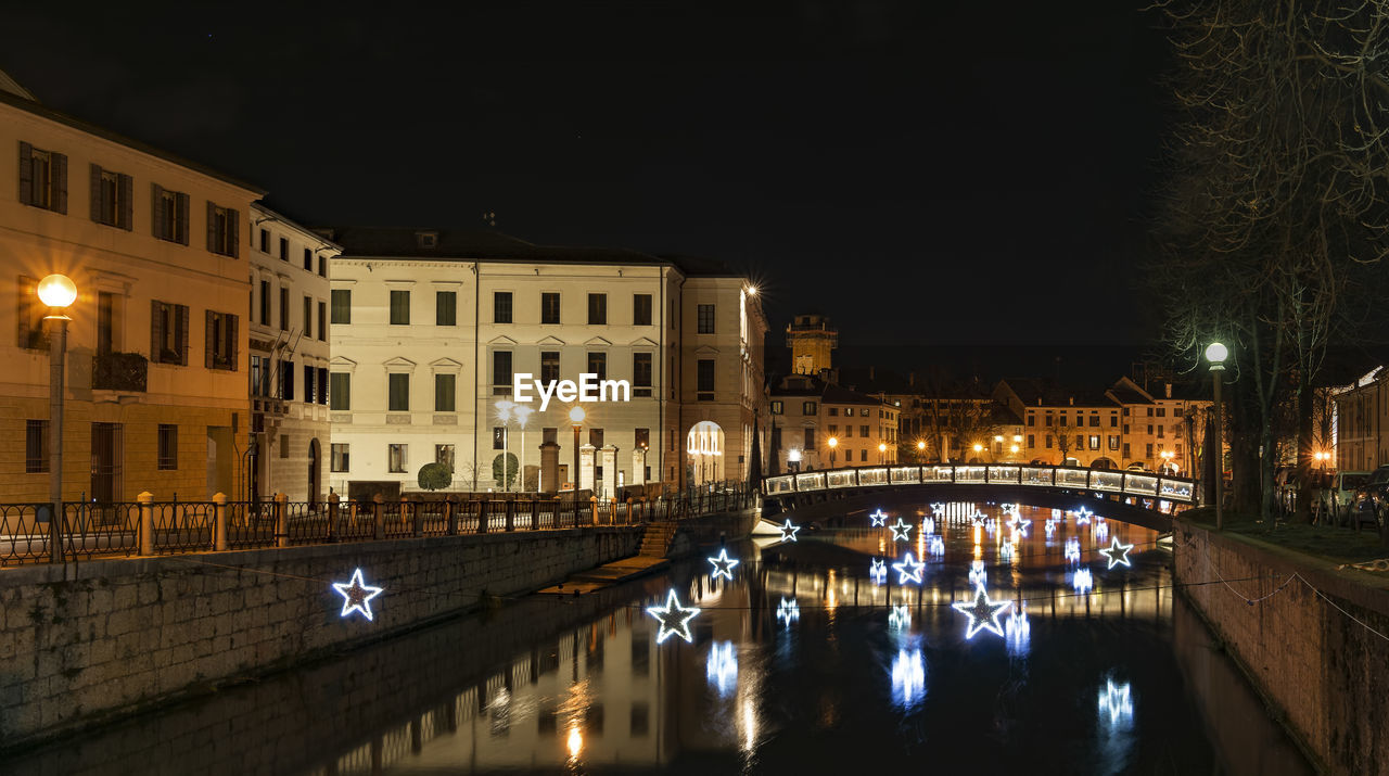 REFLECTION OF ILLUMINATED BRIDGE AND BUILDINGS IN CANAL