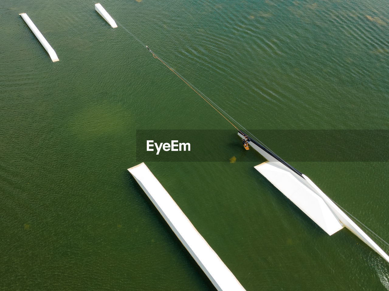 Wakeboarding surfing and doing trick in wake park from above.