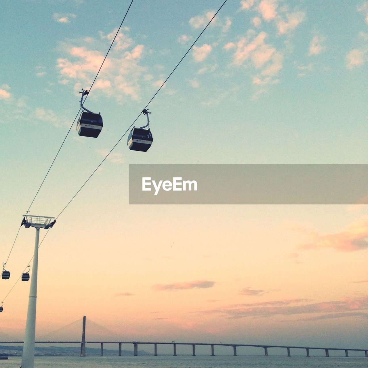 Low angle view of ski lifts over sea against sky