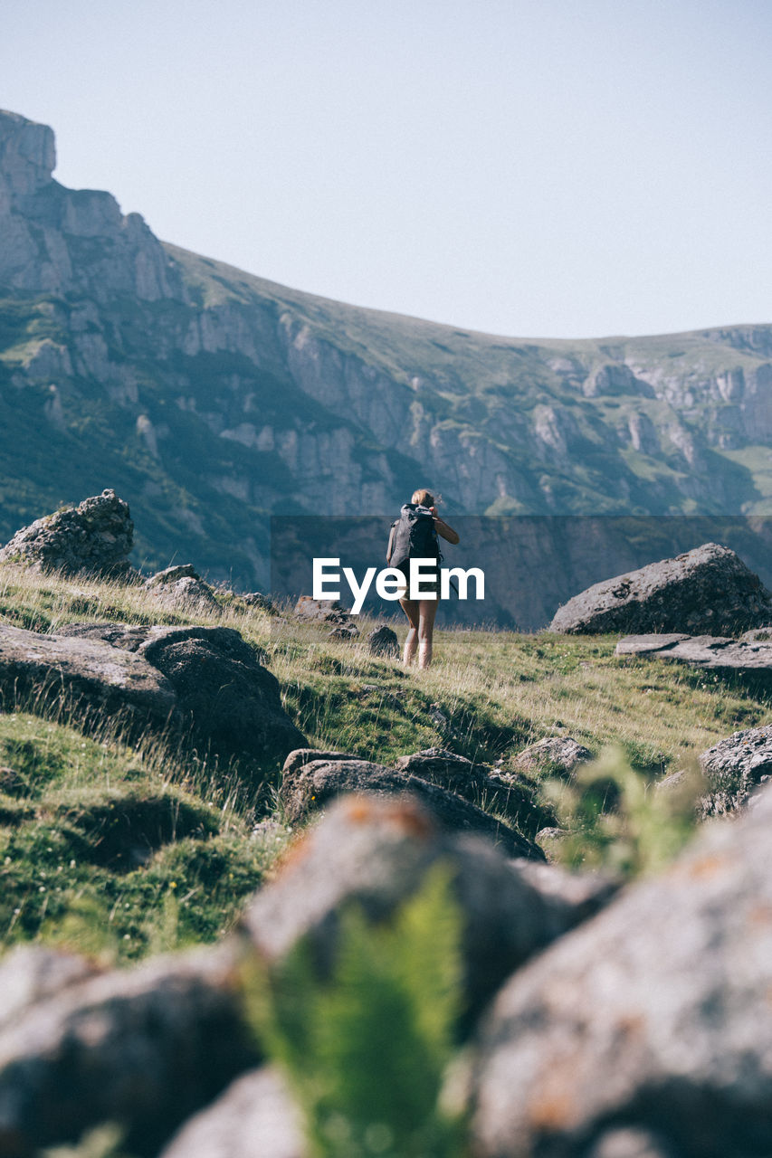 FULL LENGTH REAR VIEW OF MAN WALKING ON MOUNTAIN