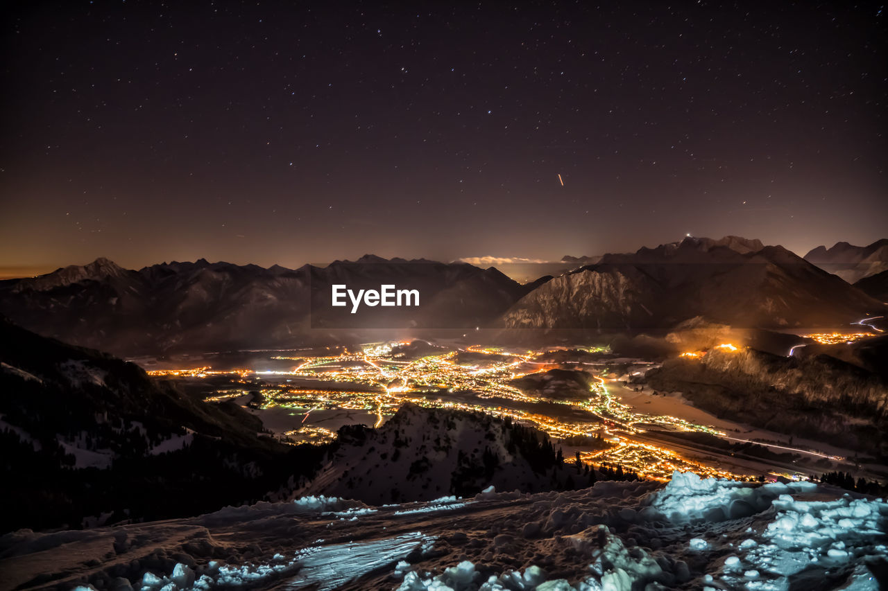 Aerial view of illuminated snowcapped mountains against sky at night