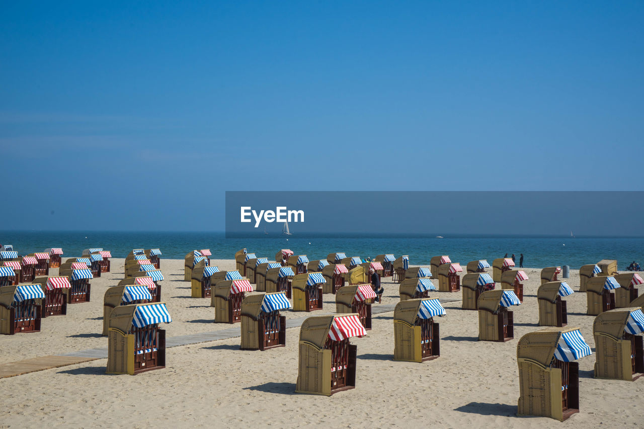 Hooded chairs on beach against sky