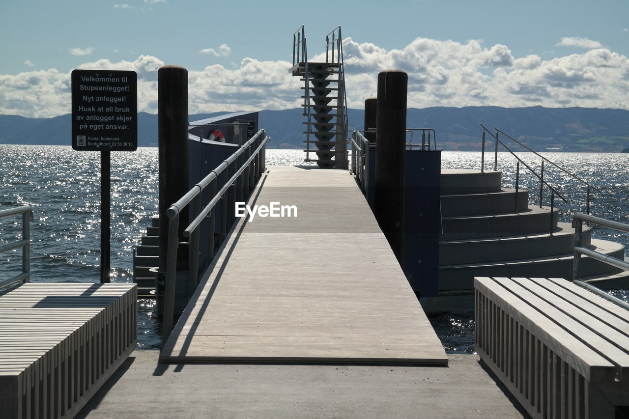 Pier with diving platform over sea against sky