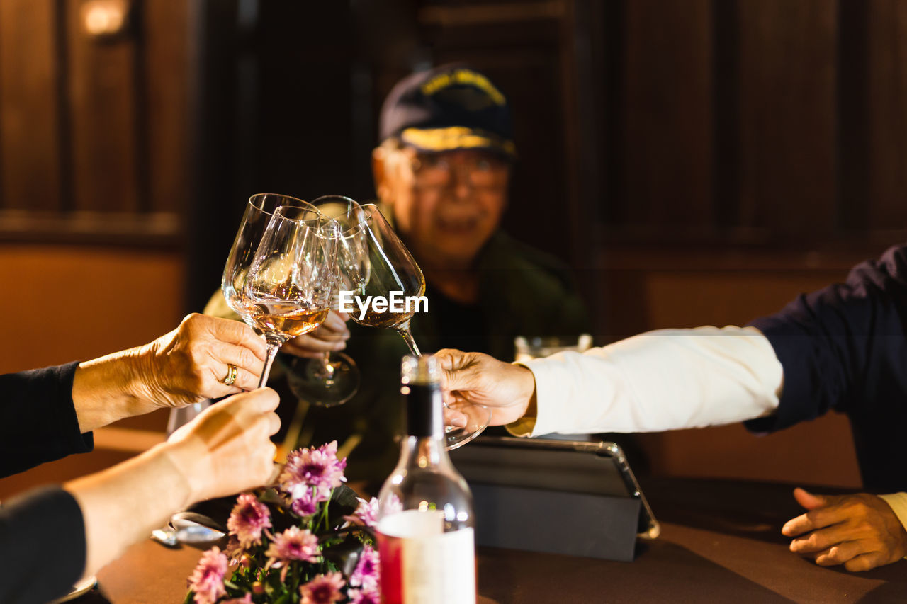 Happy family holding wine glasses toasting at dinner table.