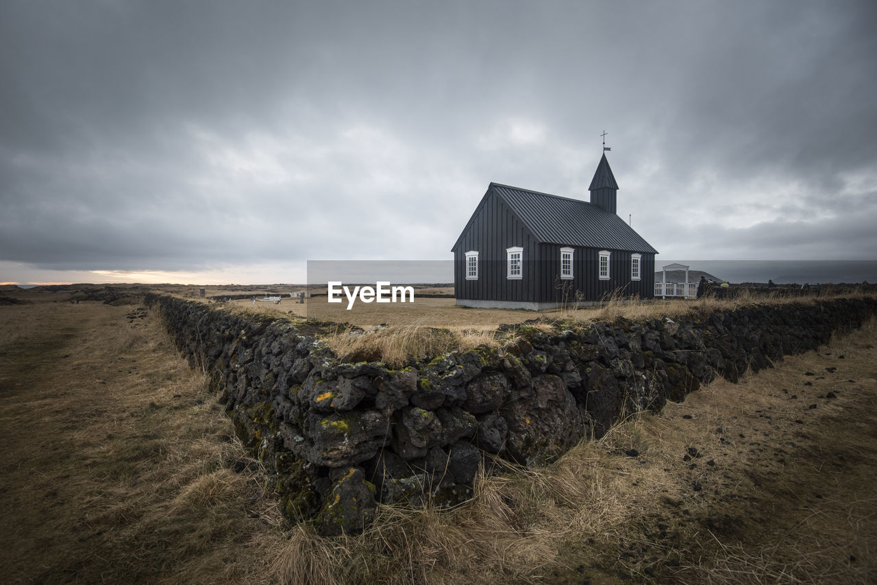 BUILDING ON FIELD AGAINST SKY