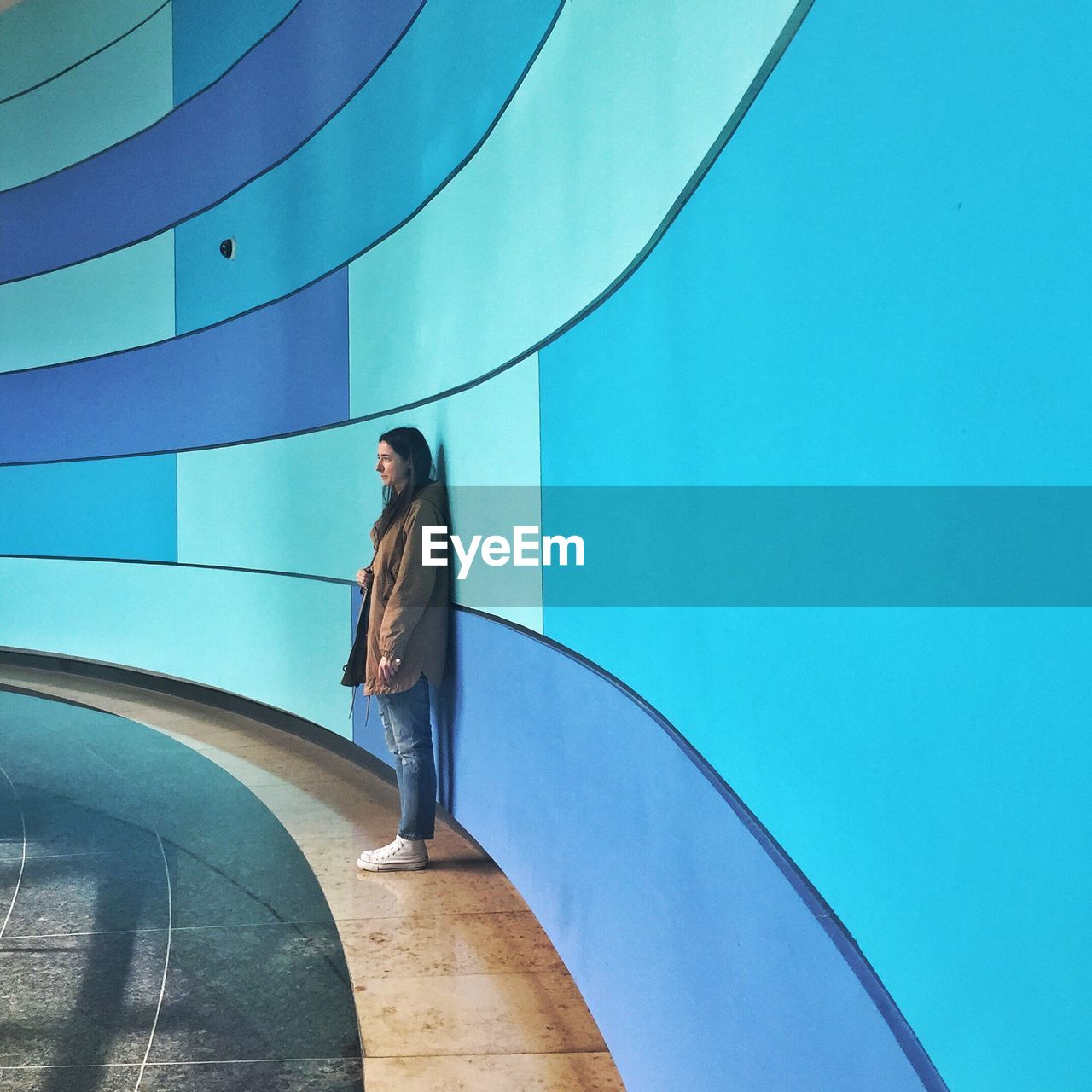 Young woman standing by wall at subway