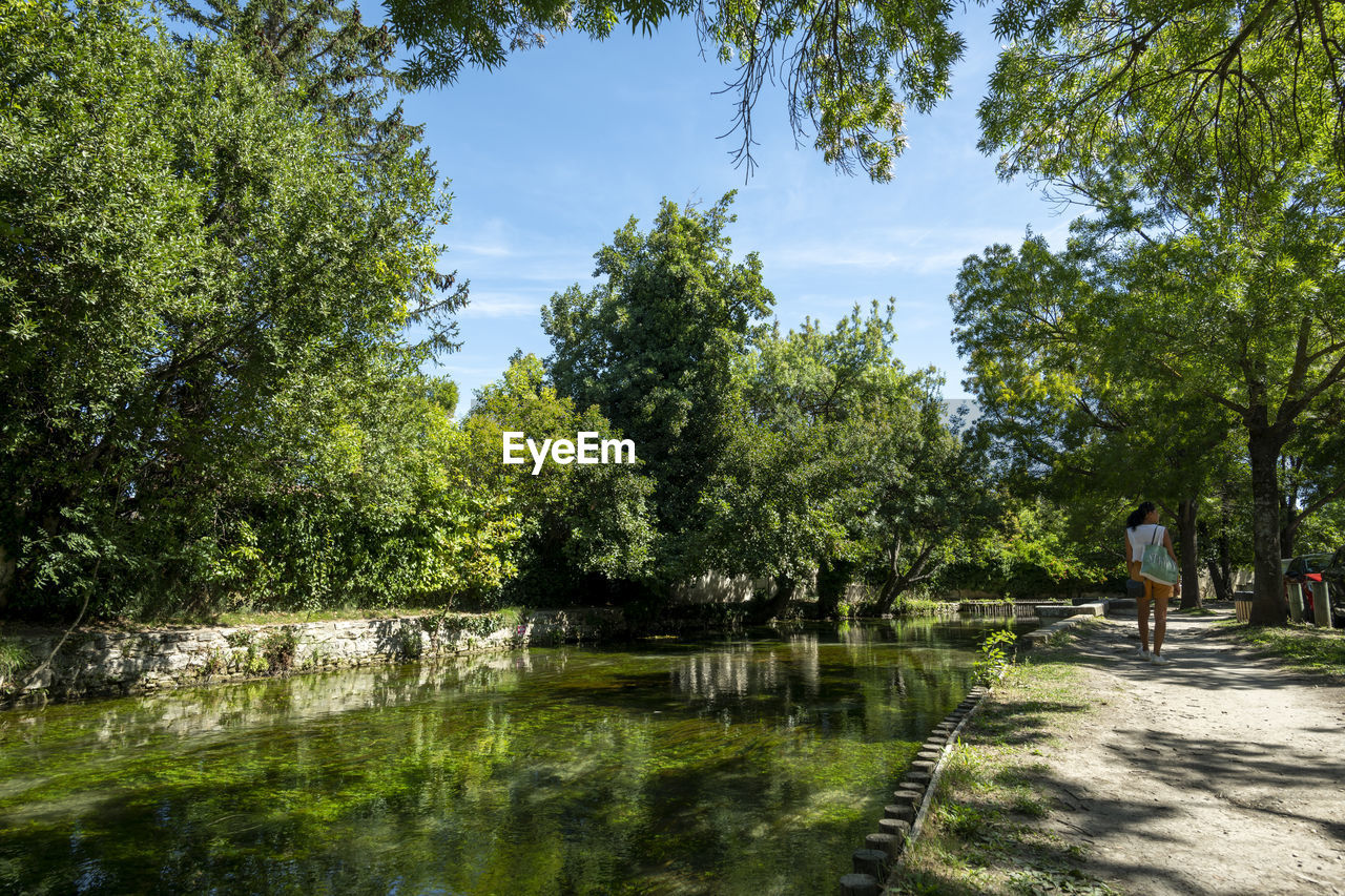 Woman walking near a water canal of l'isle-sur-la-sorgue in summer. france