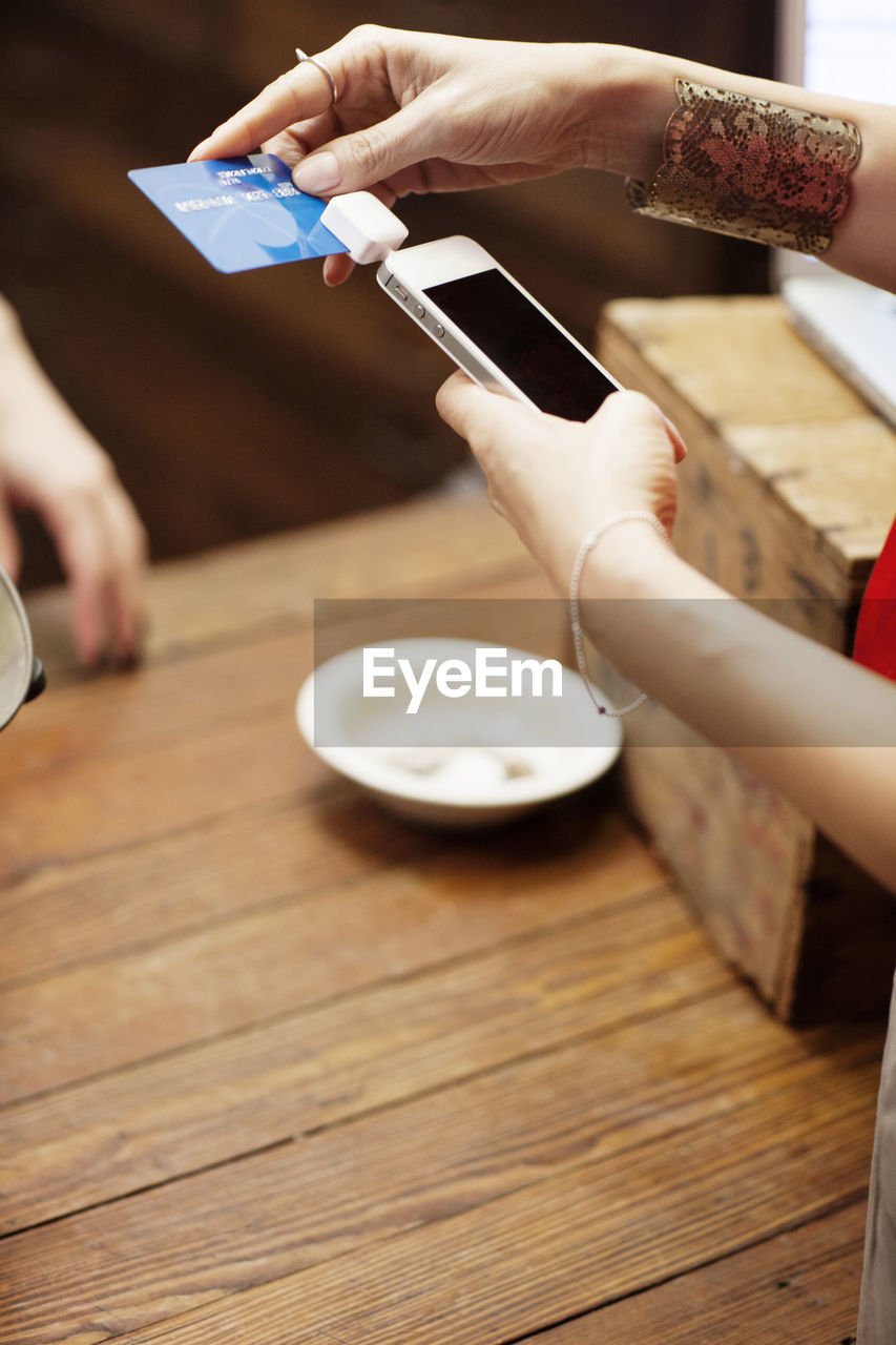 Cropped image of woman using credit card reader for paying