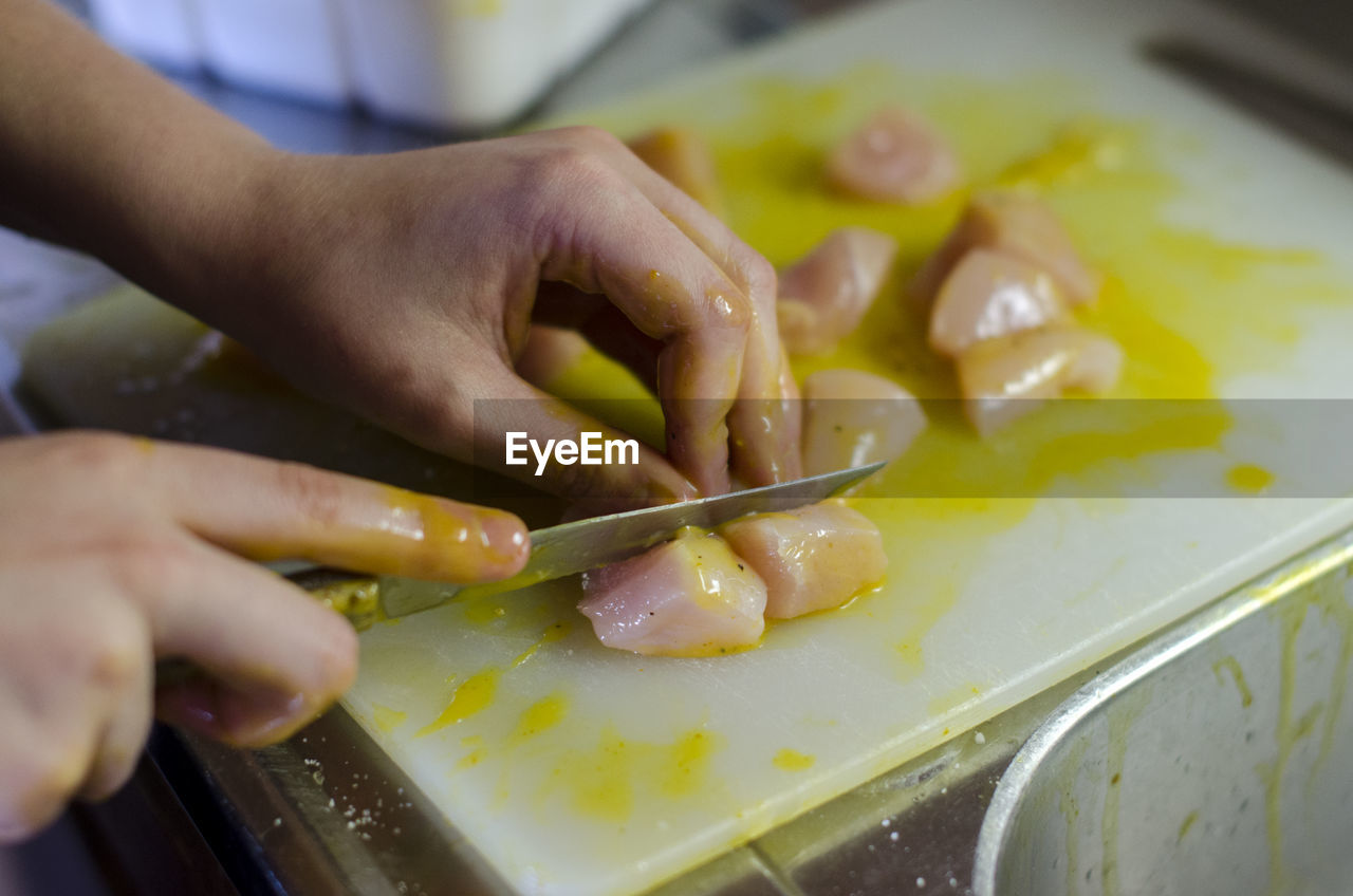 Close-up of woman slicing meat on cutting board