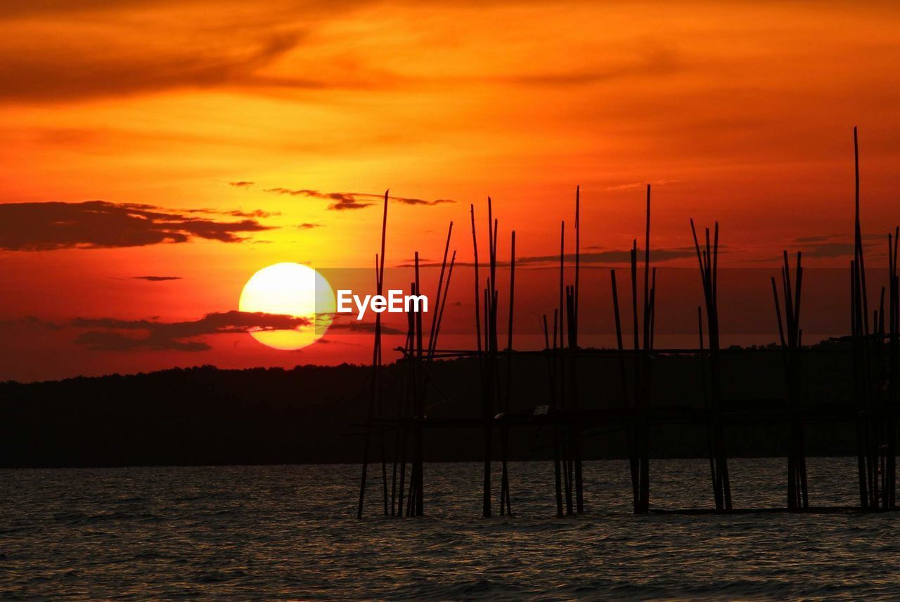 SILHOUETTE SAILBOATS ON SEA AGAINST ORANGE SKY