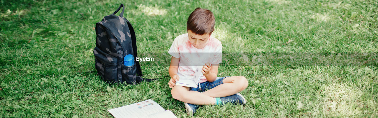 High angle view of boy sitting on grass at park