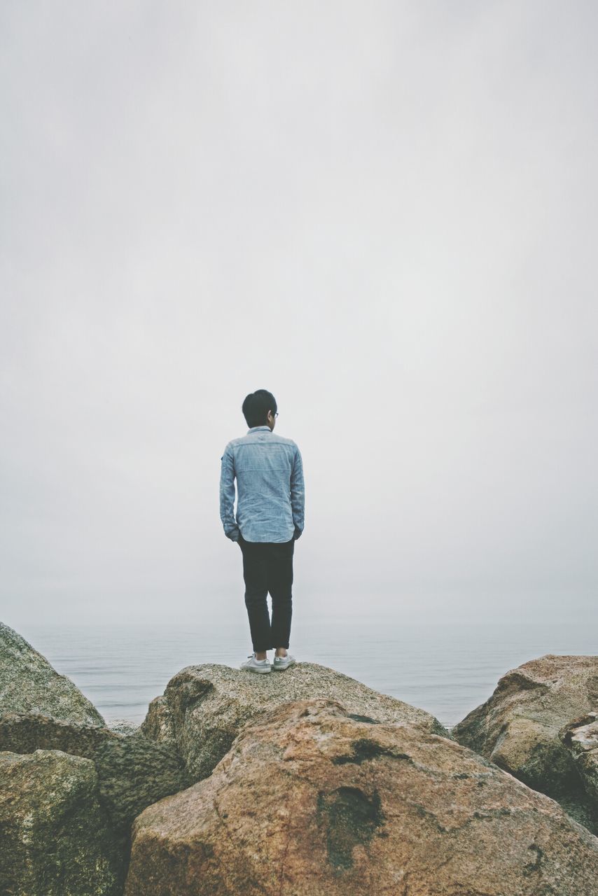 Man standing on rock overlooking sea