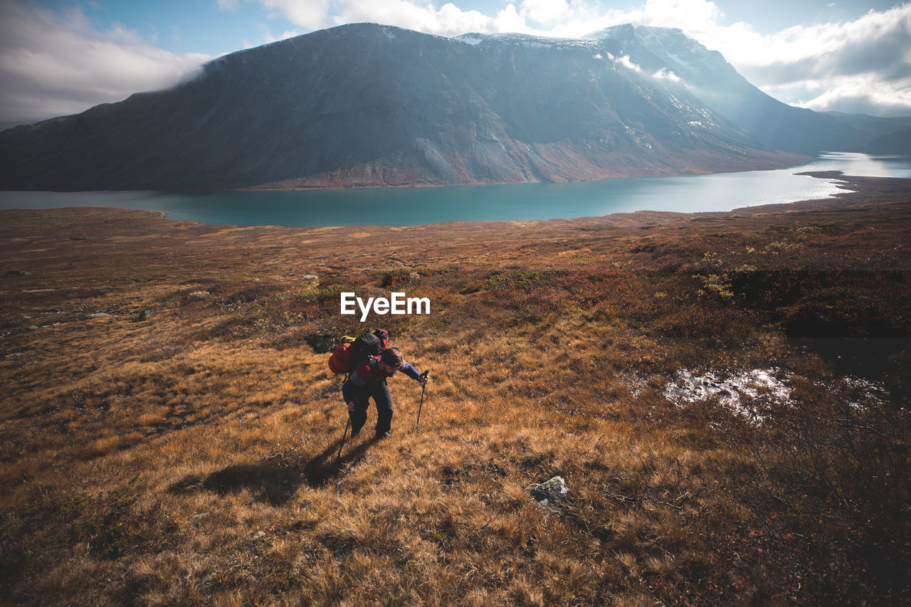 Man climbing on mountain against lake