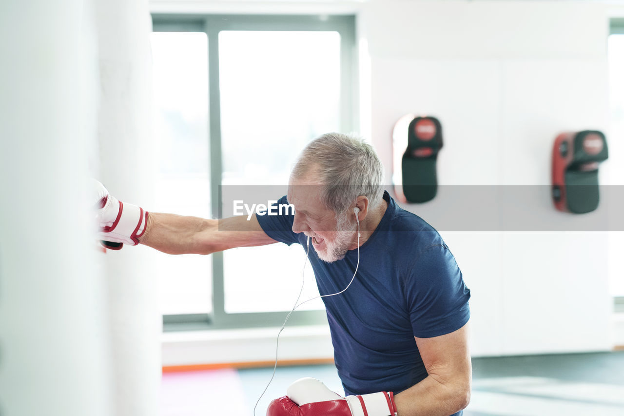 Fit senior man in boxing gloves fighting