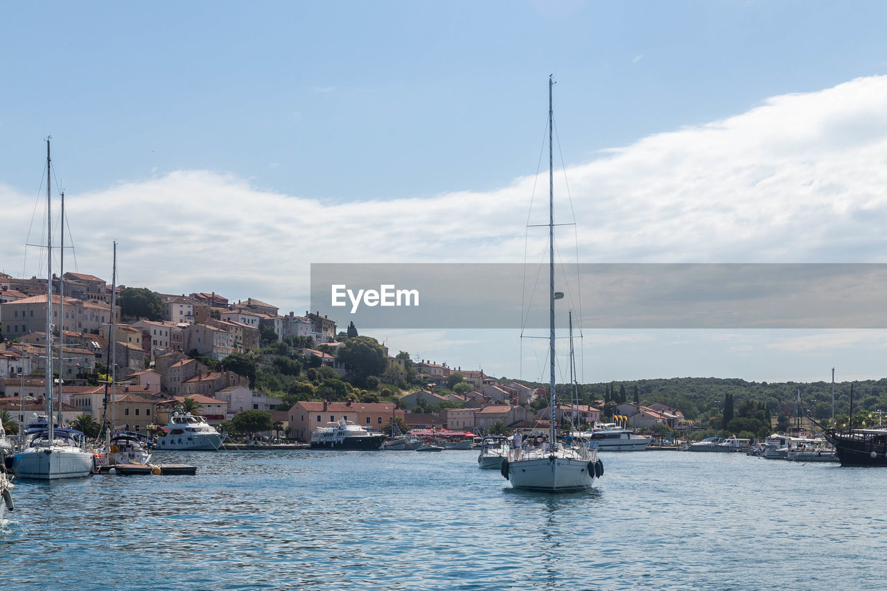 SAILBOATS MOORED IN SEA AGAINST SKY