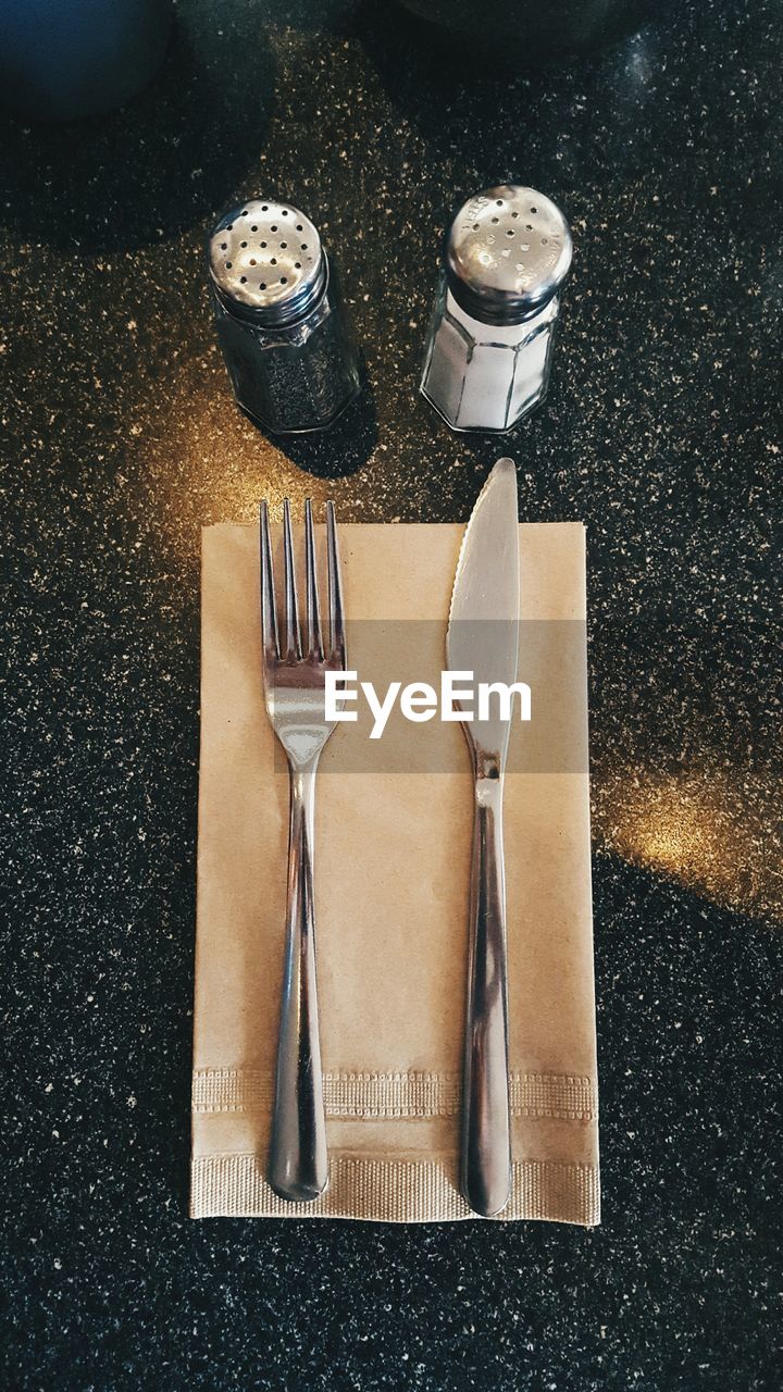 High angle view of table knife and fork on napkin at table