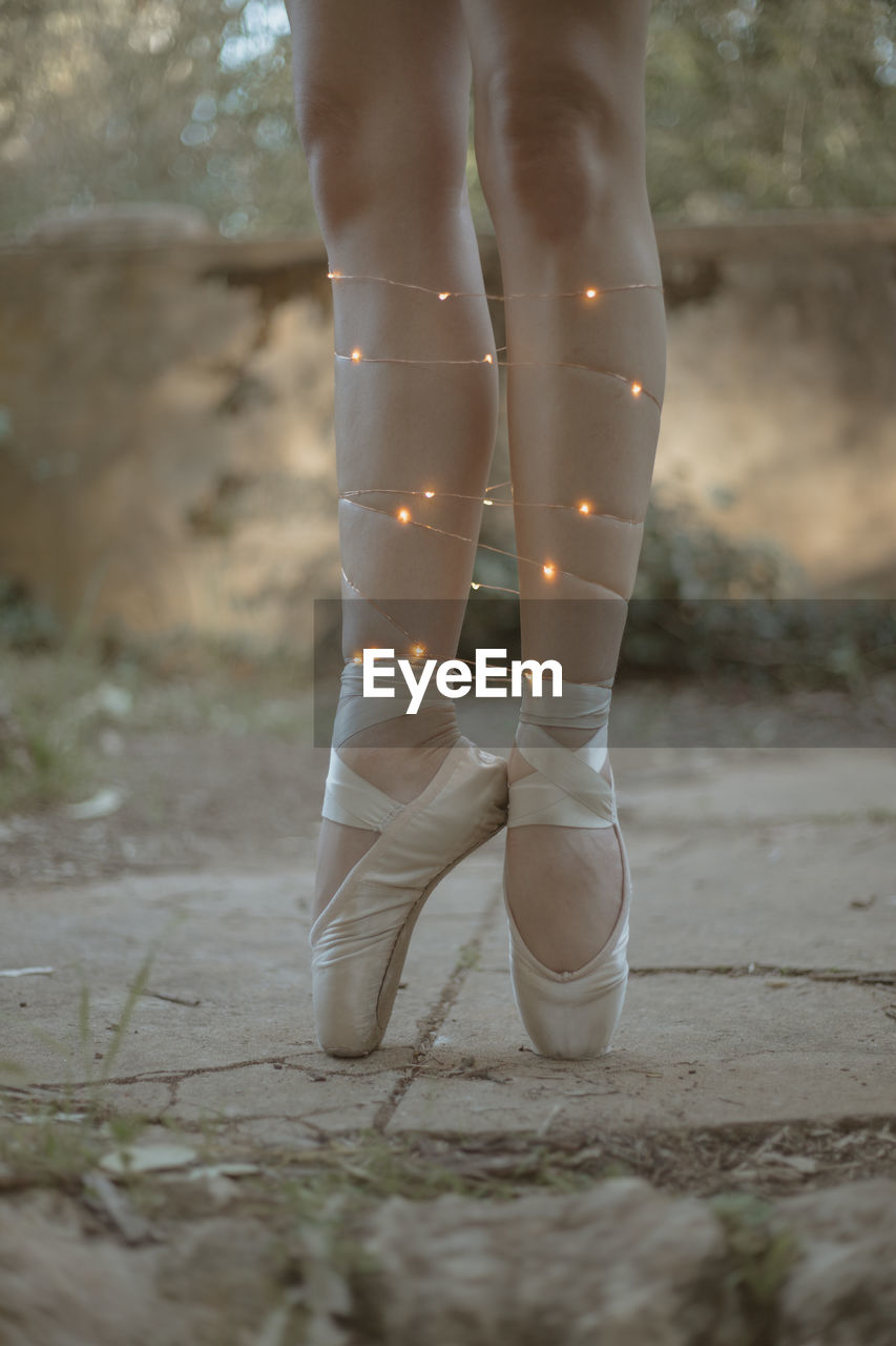 Low section of ballet dancer wearing illuminated lights standing outdoors