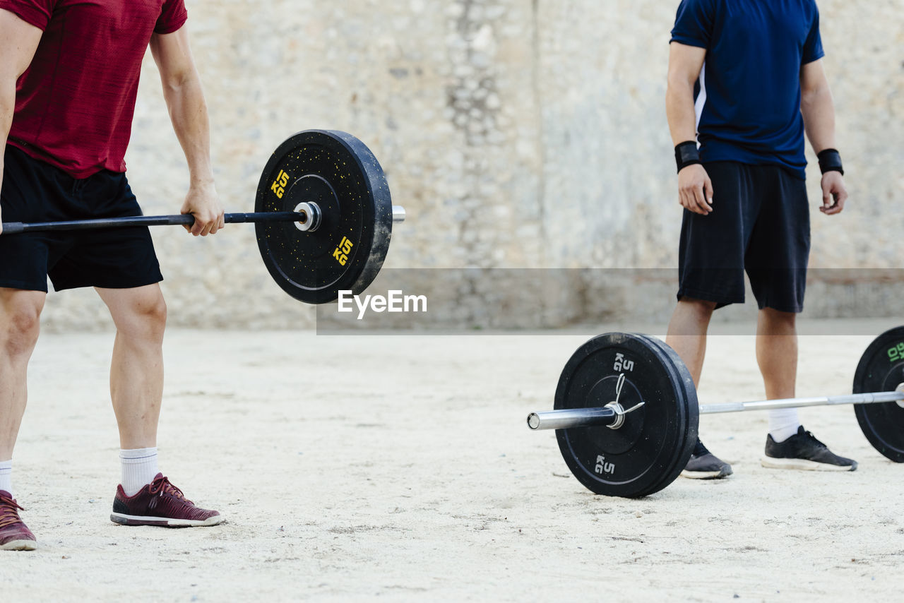 Two weightlifters lifting weights in an urban environment.