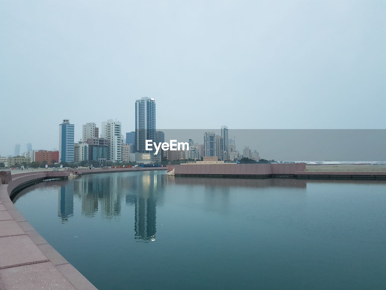 Reflection of buildings in sea side against clear sky