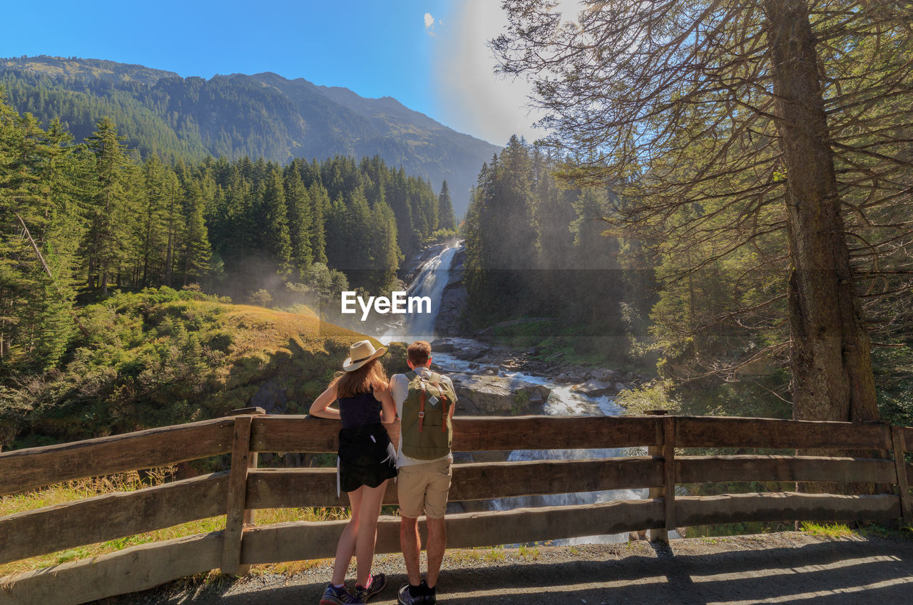 Couple looking at waterfall against trees