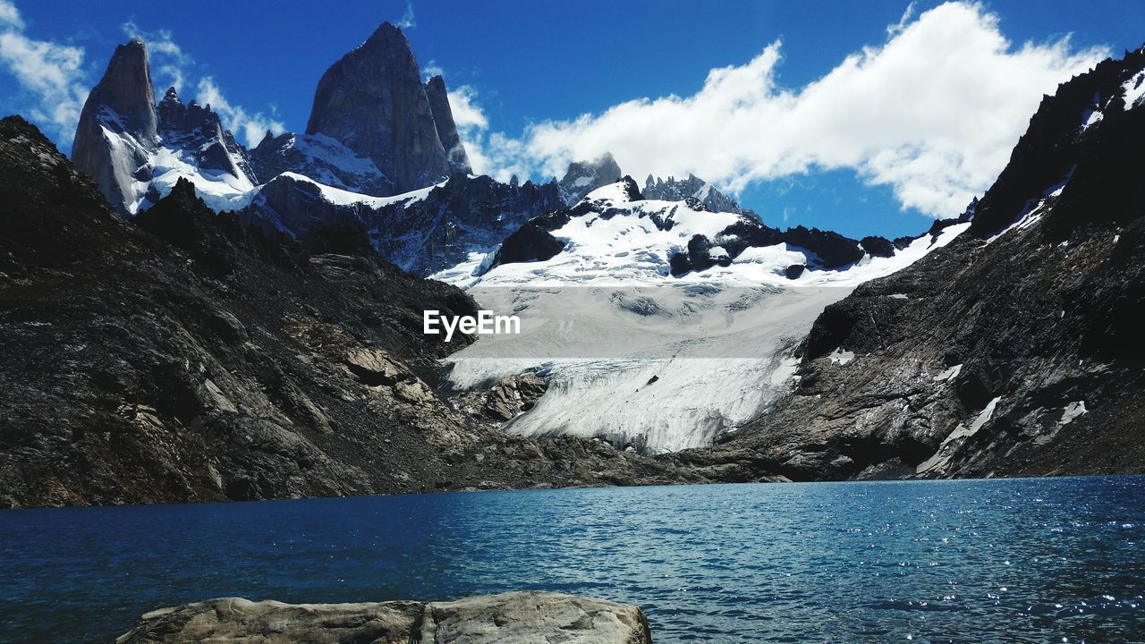 Panoramic view of sea by mountains against sky