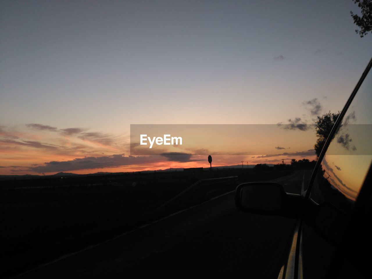 CARS ON ROAD AGAINST ORANGE SKY