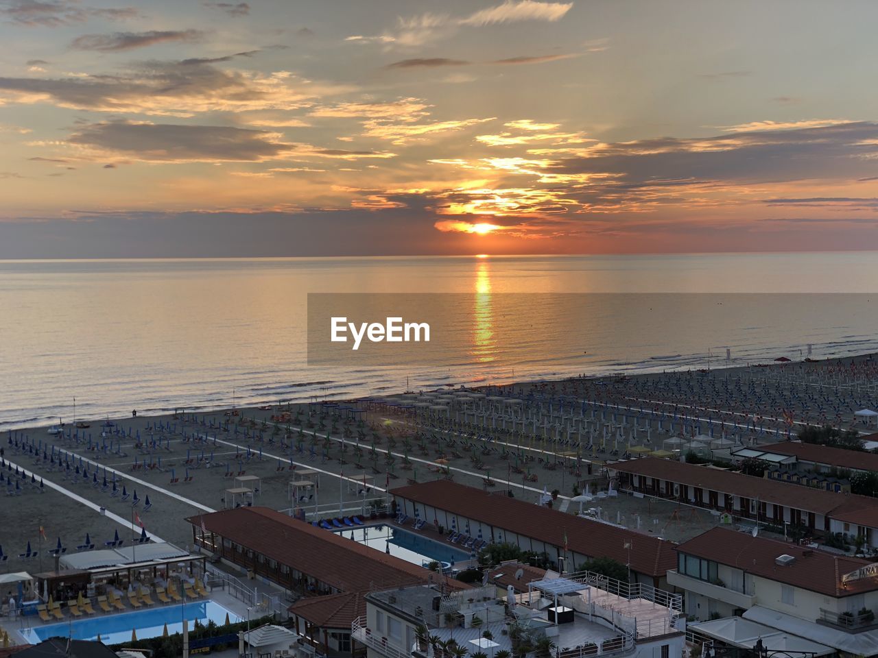 High angle view of sea by buildings against sky during sunset