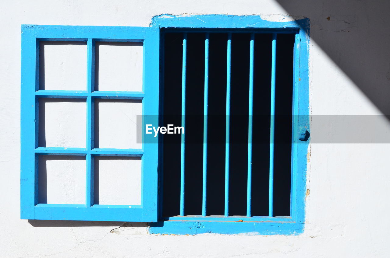 Open blue window on white wall
