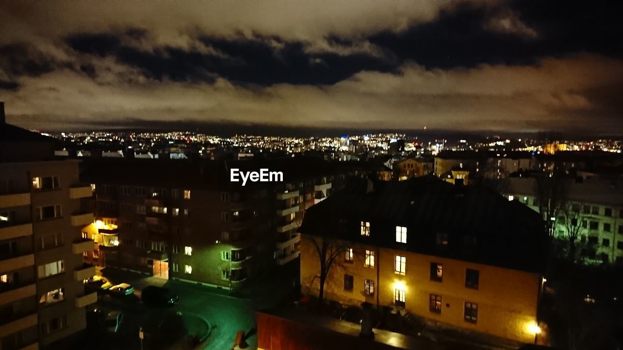 HIGH ANGLE VIEW OF ILLUMINATED CITYSCAPE AGAINST SKY